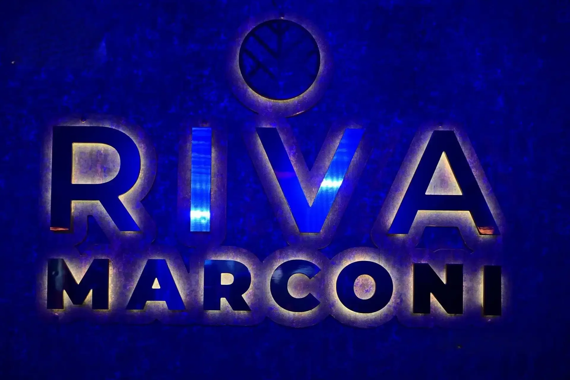 Insegna luminosa di Riva Marconi su parete blu