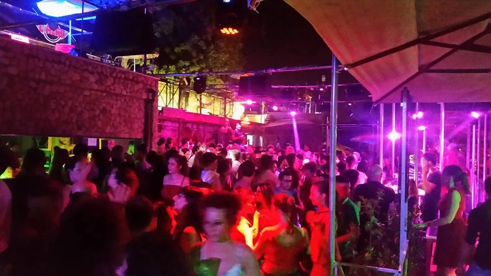 Serata affollata nell'area coperta del locale con luci rosa e viola