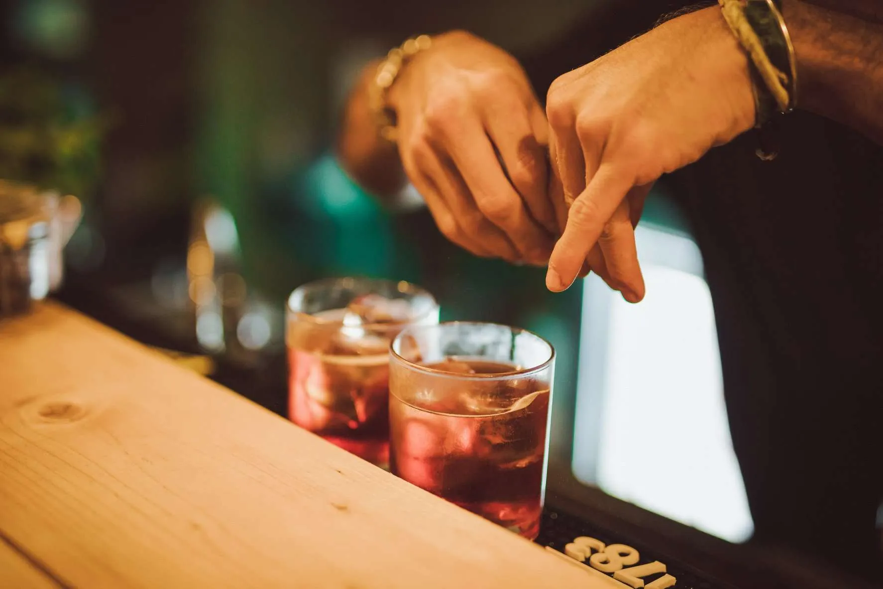 Barman al lavoro con due cocktail sul bancone in legno della Terrazza Gianicolo