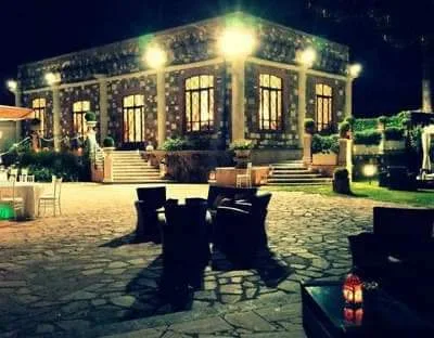 Esterno serale della villa con tavolini e sedute in pietra