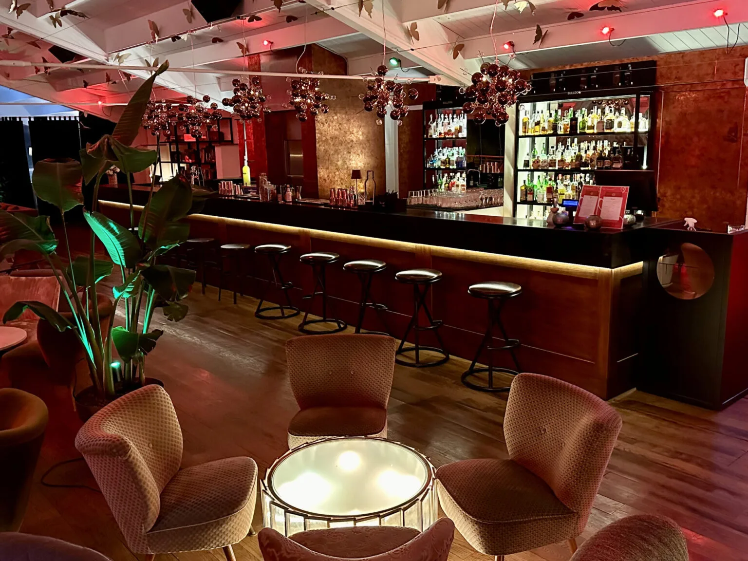 Il lungo bancone bar del The Roof con gli sgabelli e i tavolini luminosi