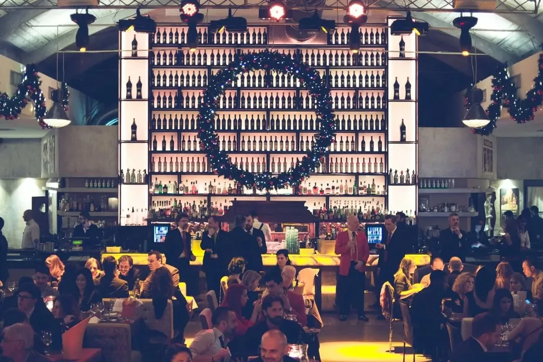 La sala del Vinile Roma con il bar a parete e i tavoli della cena